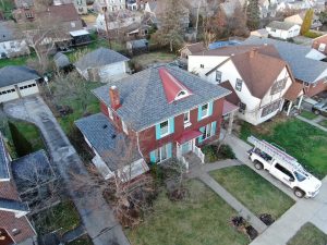Shingle roof installed on a home with teal shutters and red roof awning