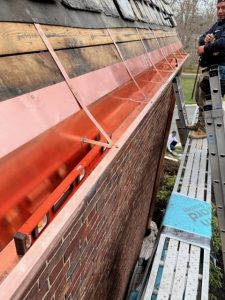copper gutters being installed on a home with slate roof tiles