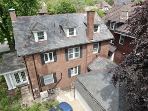 home with slate roof installed, next door is a home with clay roof tiles