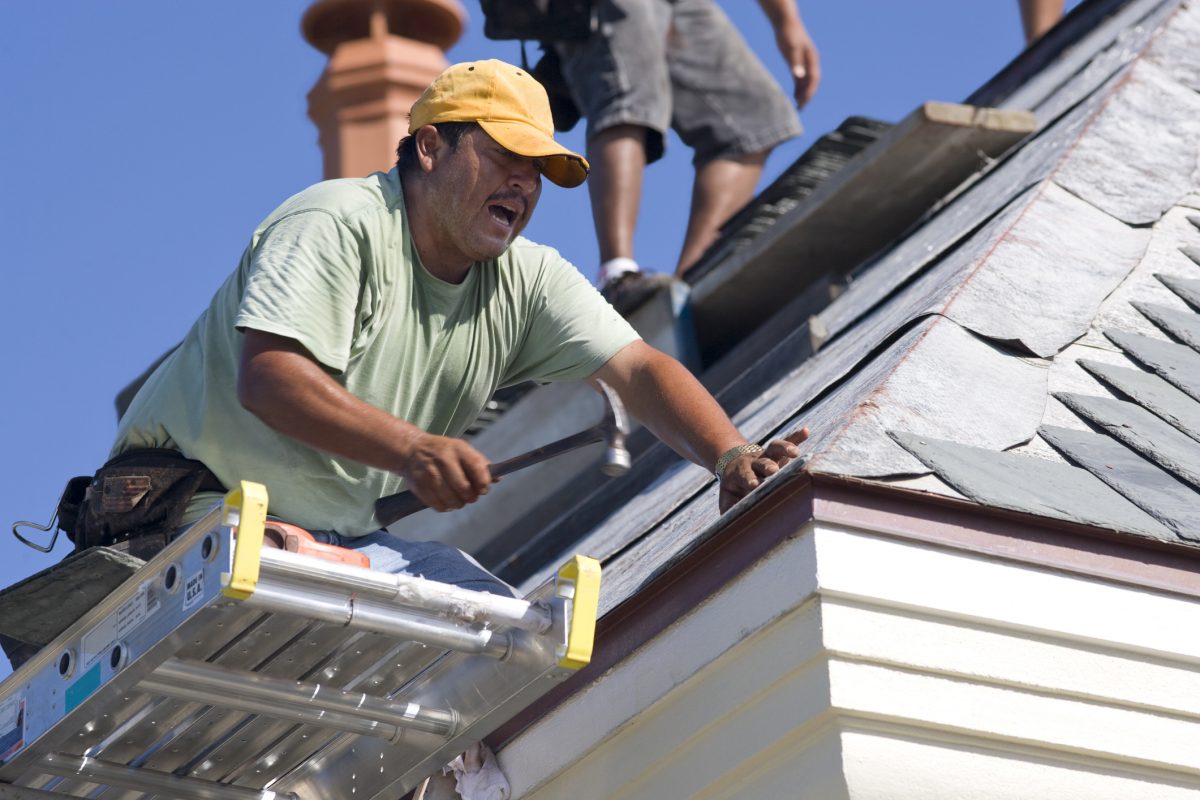 Roofer laying slate on a home.